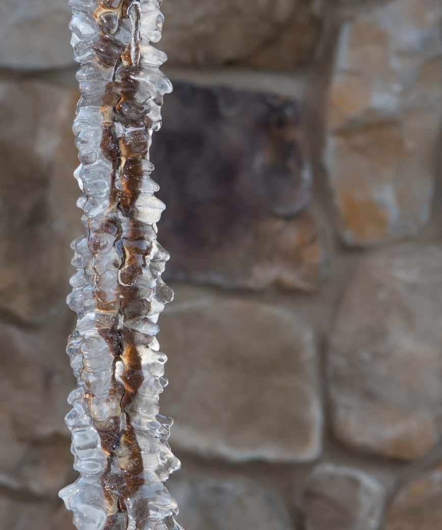 A frozen rain chain in a snowy environment