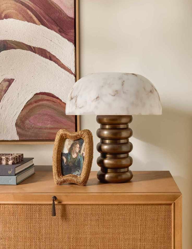 Lulu and Georgia rattan photo frame pictured alongside a bronze-based, marble-shaded table lamp from the brand's fall 2025 collection