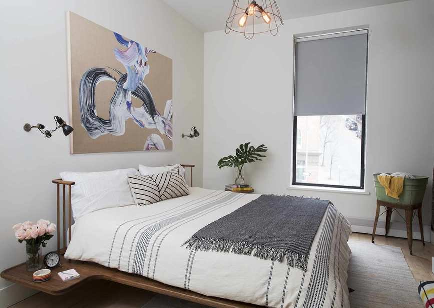 A bedroom with a large wooden bed frame with a built-in headboard with spindles and a nightstand platform