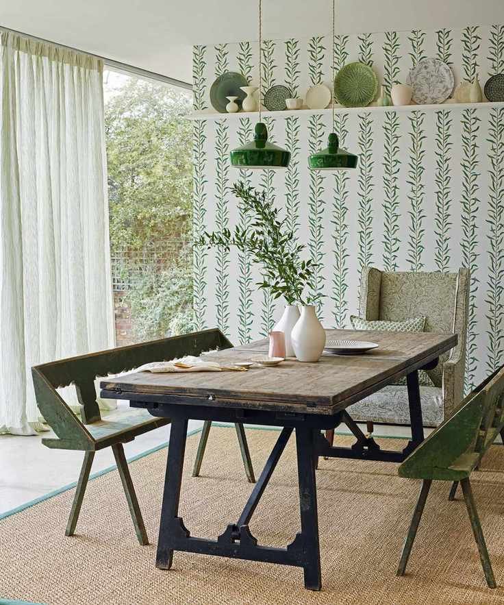 Nature-inspired dining room with leaf pattern wallpaper and rustic dining table.