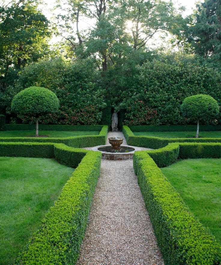 parterre of box hedging with gravel paths around a fountain and statue at far end