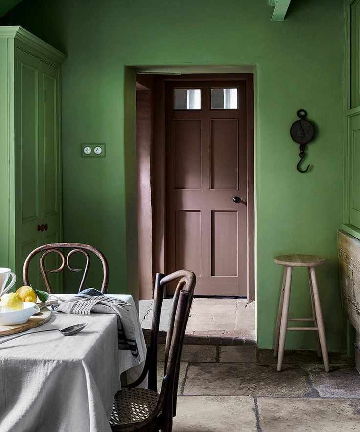 Traditional dining area with green walls and stone flooring.