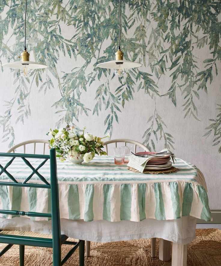 Dining room adorned with a green botanical mural and a striped tablecloth.