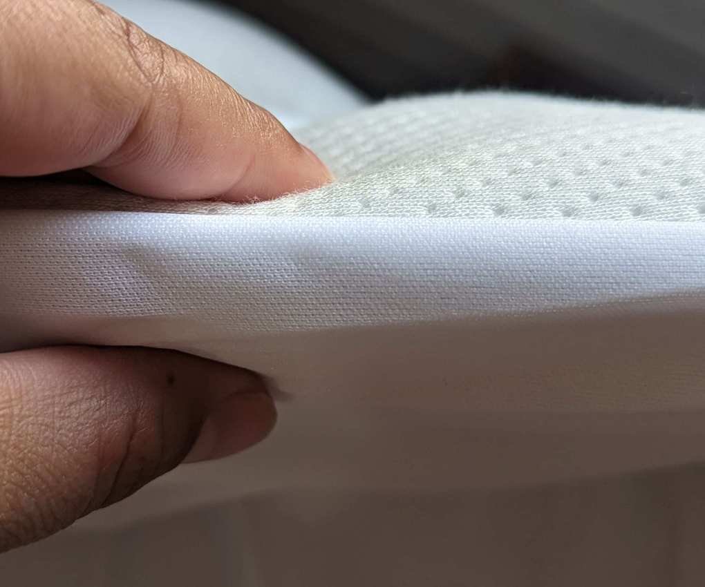 A hand pinching the Helix Plush Mattress Topper.