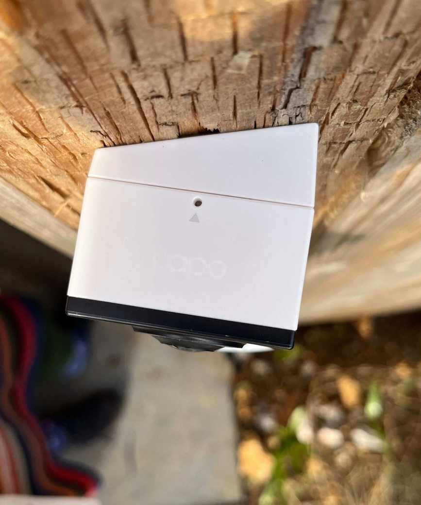 Above photograph of the Tapo D210 Video Doorbell mounted on a wedge mount, on a wooden surface.