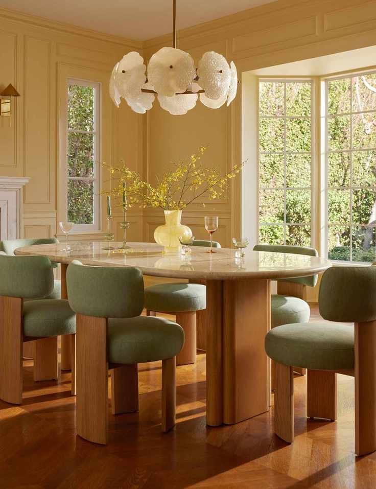 Sunny butter yellow dining room styled with sculptural mid-century furniture and a floral chandelier