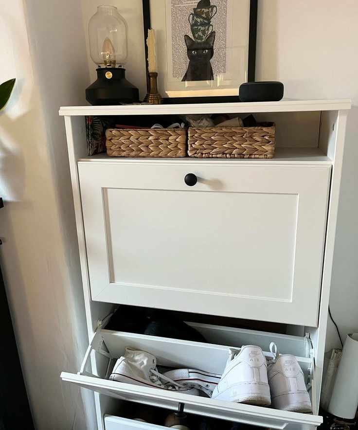 A white slimline shoe cabinet with shoes inside.