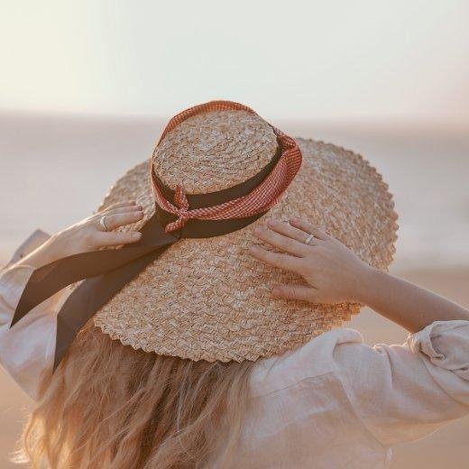Woman on beach wearing a wide brimmed hat for sun protection Woman on beach wearing a wide brimmed hat for sun protection