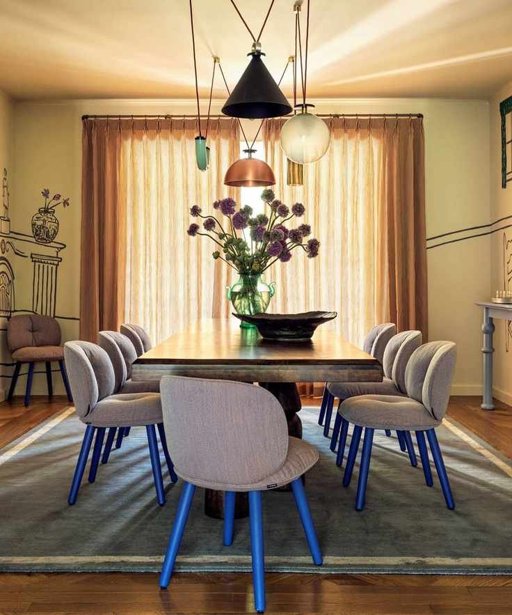 Dining room with painted mural, large wooden table and grey and electric blue dining chairs