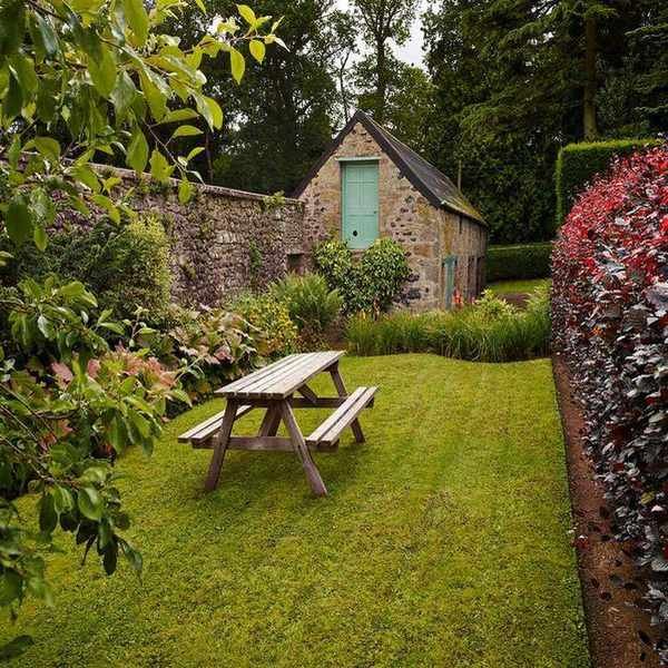 Vibrant flower beds alongside a lawn featuring a picnic table.