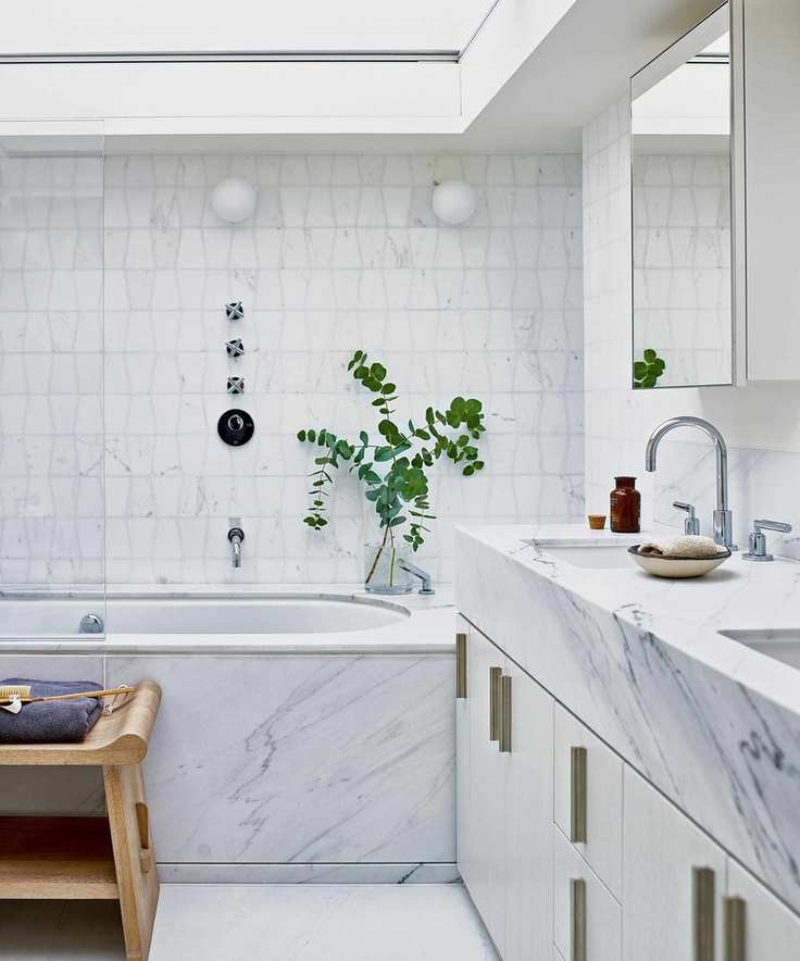 marble and tile bathroom with double vanity and bathtub