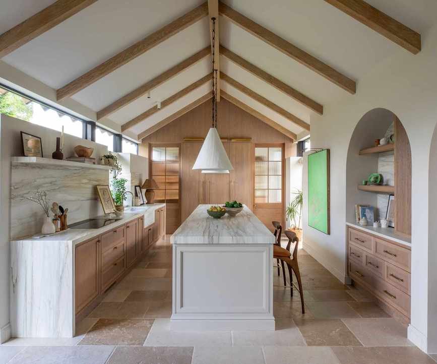 A midimalist kitchen with wooden cabinetry and marble surfaces