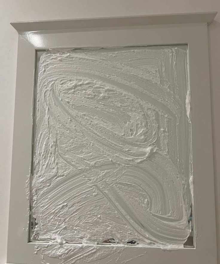 A mirror covered in shaving foam with a white wooden border