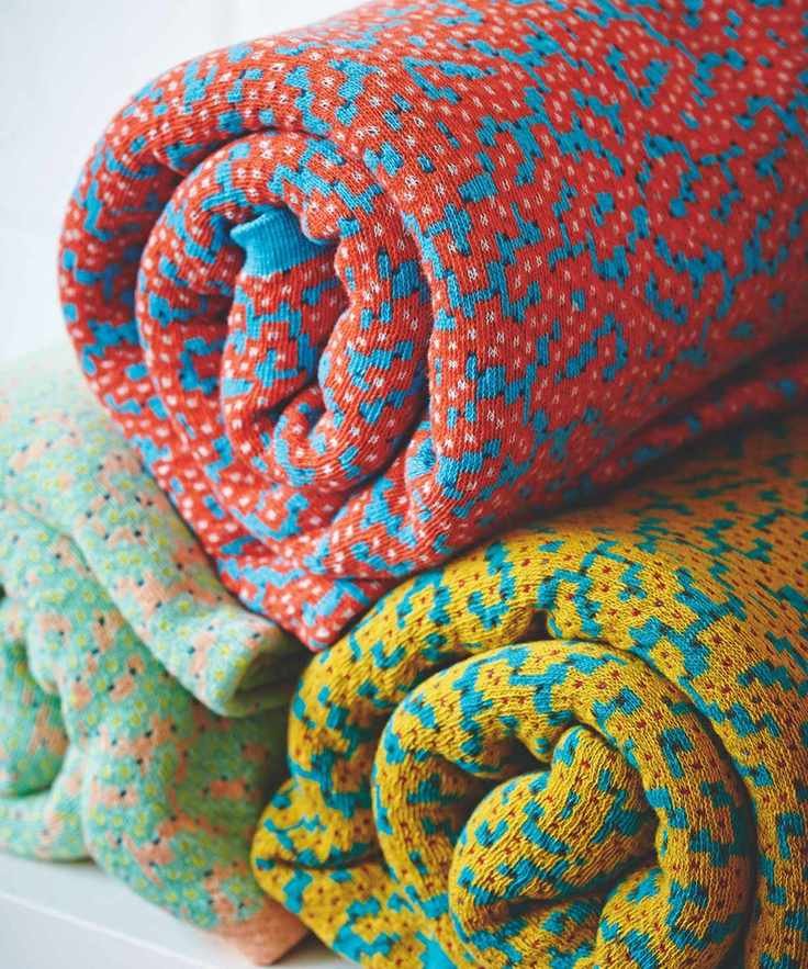Three colorful rolled up blankets in red, yellow, and green.