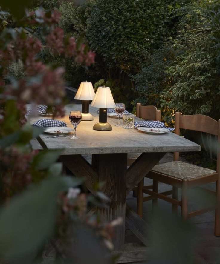 marble table surrounded by hedges with a tablescape with two portable lamps