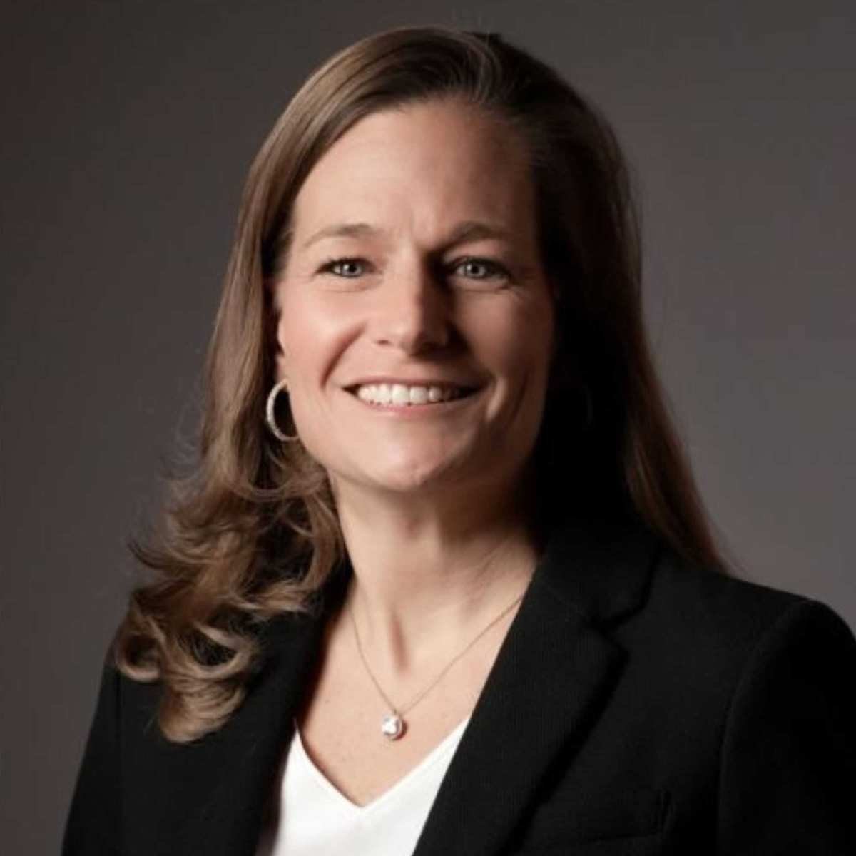 A picture of Marla Mock - a woman with brown hair wearing a black blazer and white top, smiling into the camera