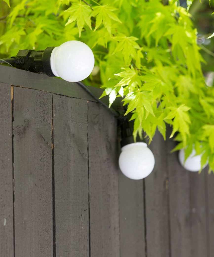 Fairy lights wrapped around a wooden fence.