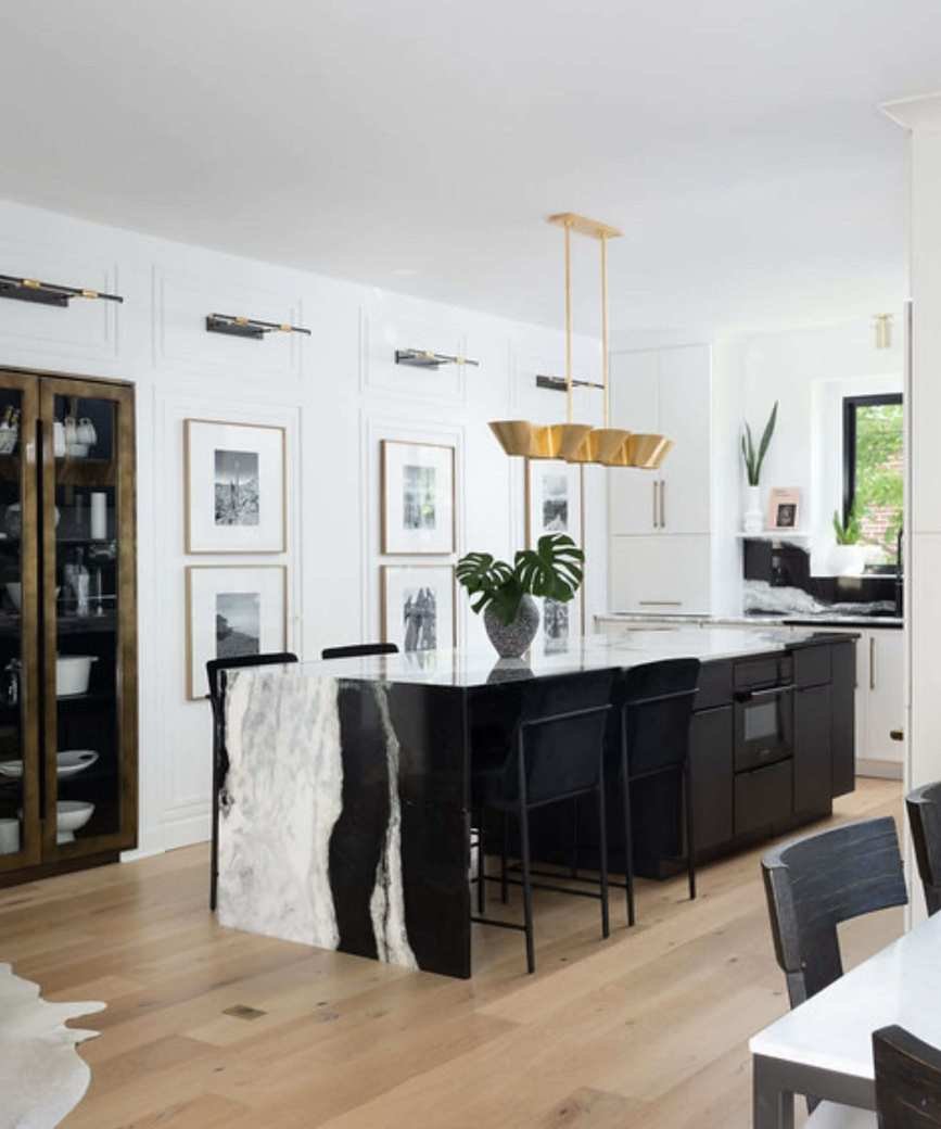 A black, white, and wooden kitchen with countertop cabinets and a statement black and white marble waterfall countertop