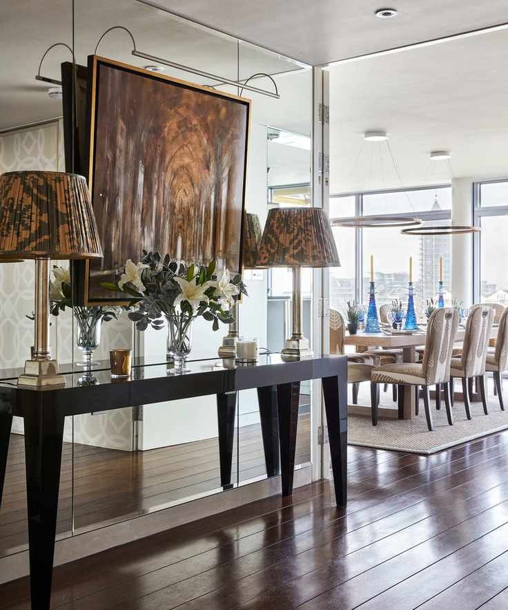 A hallway lighting idea with table lamps on a console table, backed onto a mirrored wall