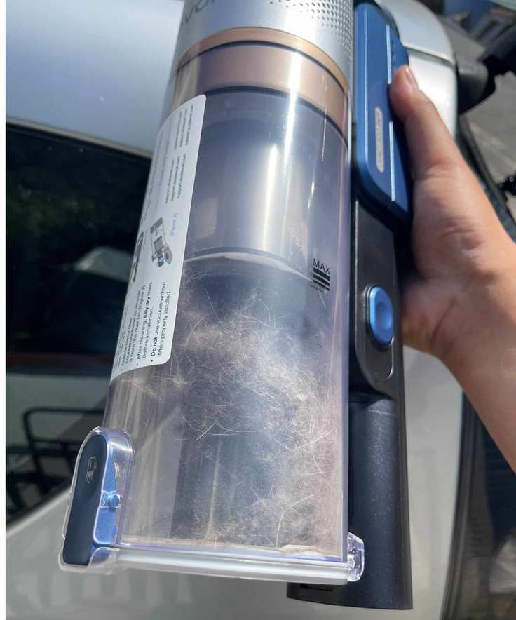 Levoit LVAC-300 dustbin filled with pet hair in front of a car.