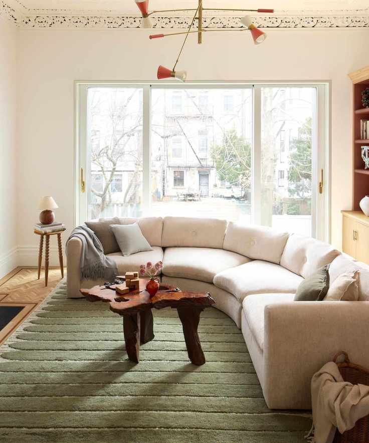 Bright living room with curved, white sofa, wooden and natural coffee table
