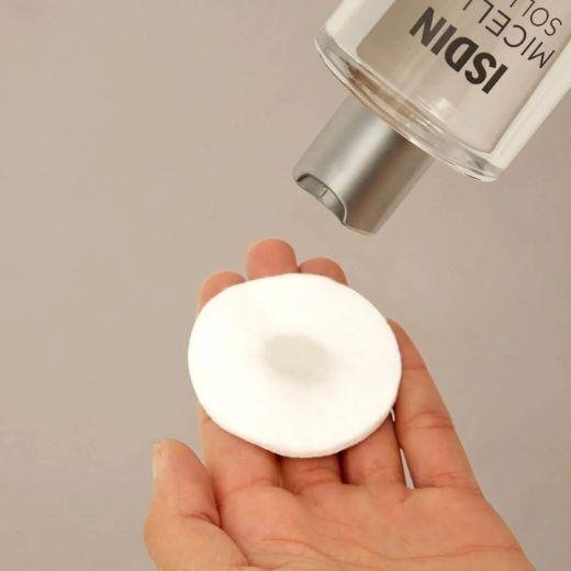 ISDIN Micellar Solution being applied to cotton round for makeup removal on the eyebrows