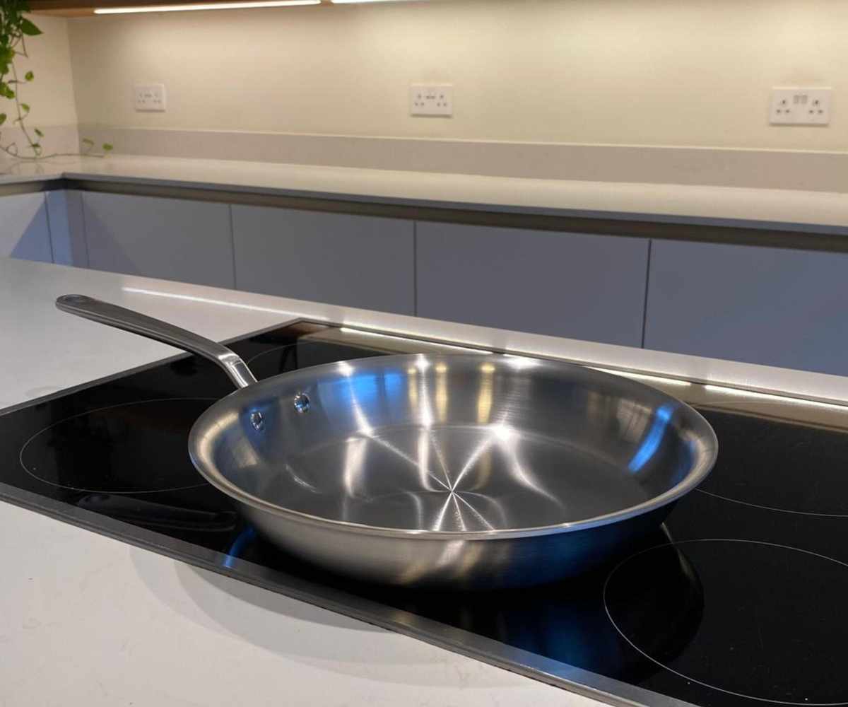 A MadeIn stainless steel pan on a black electric stove in a kitchen