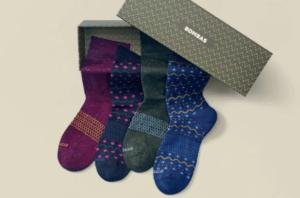 Four pairs of patterned socks are displayed on a gift box.