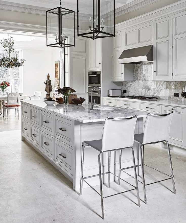 A white kitchen where marble backsplash ideas seamlessly flow into the countertops and island.