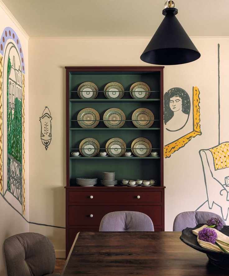 Dark wooden dresser in a dining room with hand painted murals