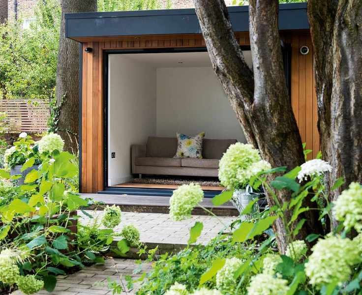 tree underplanted with hydrangeas and garden studio
