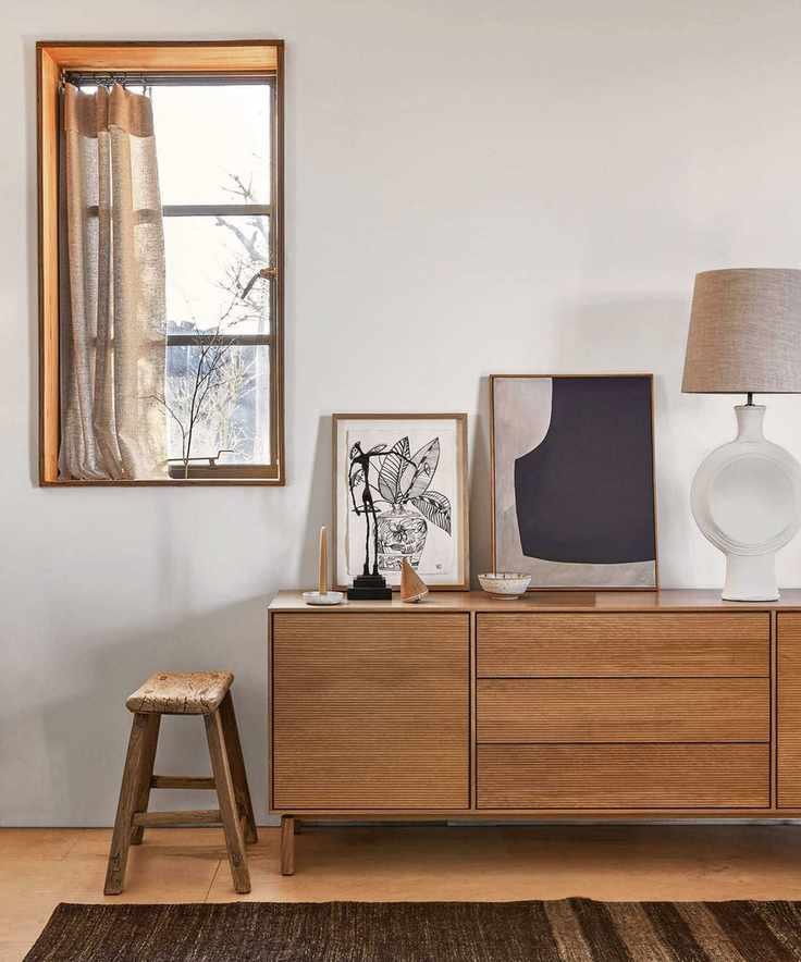 wood sideboard with white lamp and artworks