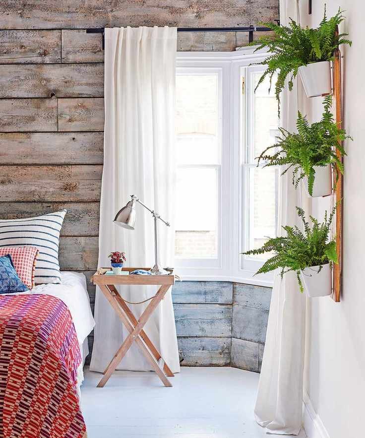 Bedroom ideas for teenagers with rustic gray-washed wood panels, house plants and red patterned bed throw.