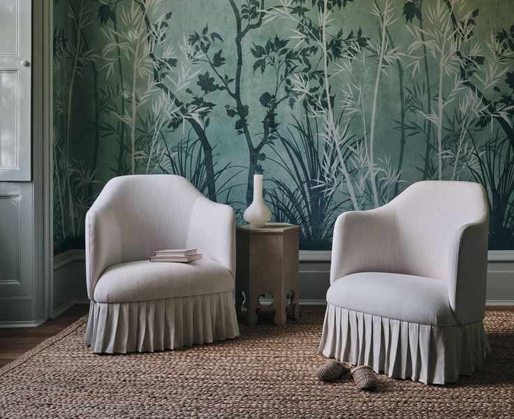 green botanical wallpaper in a room with two chairs upholstered in a pale neutral fabric