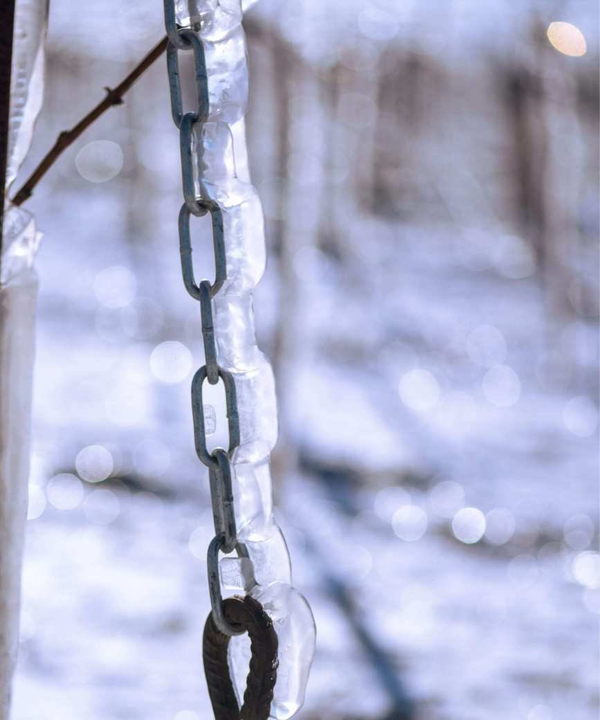 A frozen rain chain in a snowy environment