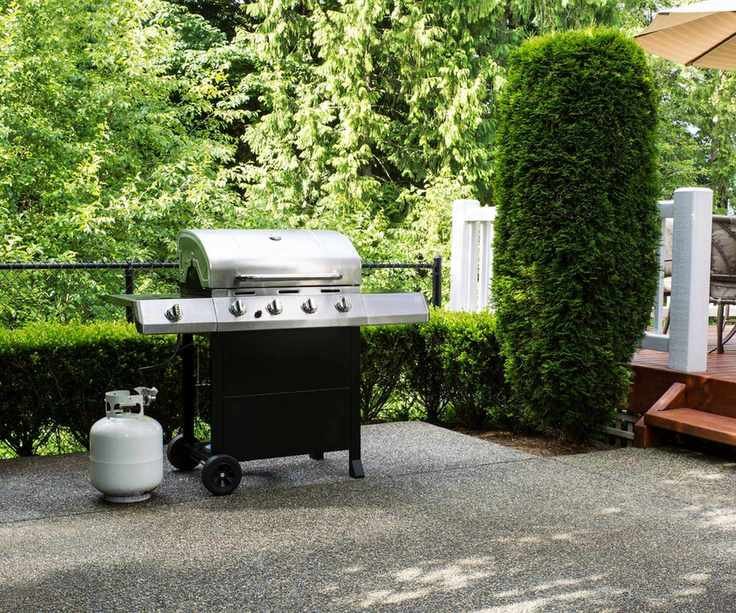A white propane tank next to a gas grill