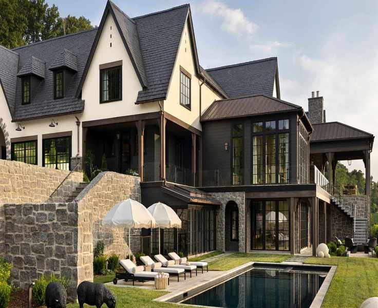 Exteriors of a large new build home with a gray tiled roof, cream walls and a pool in front