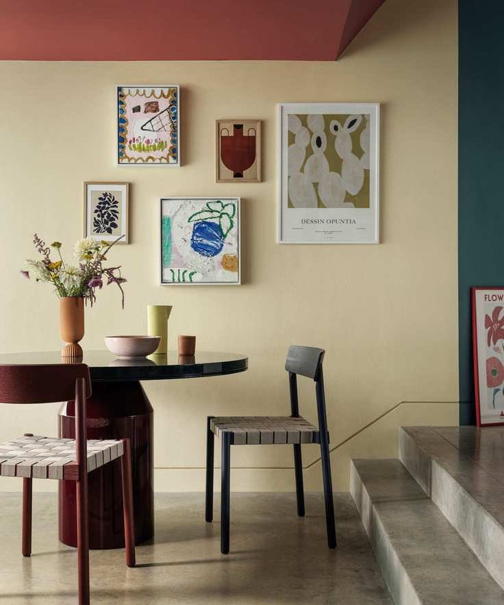 Dining room with a red ceiling and blue painted walls, featuring a stone floor and colorful artwork