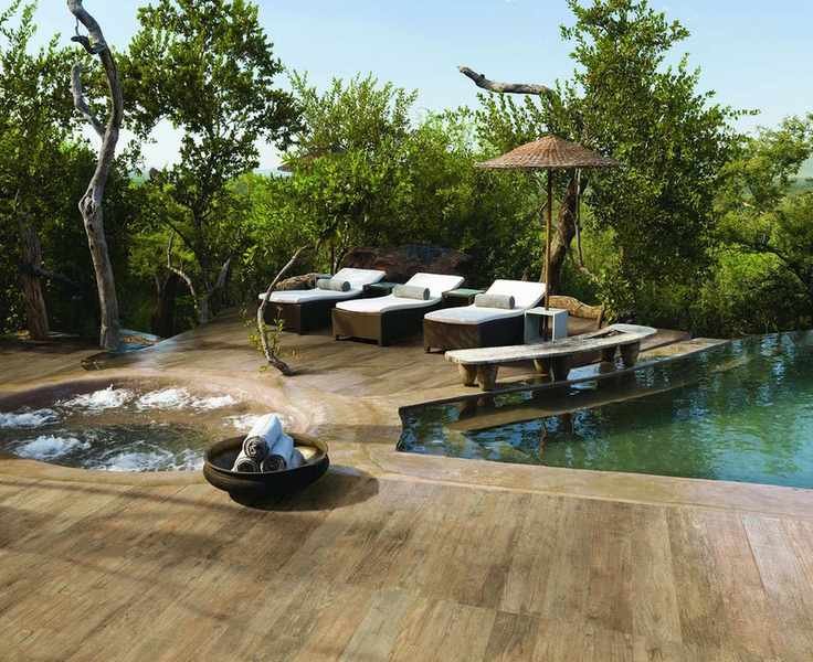 An outdoor pool and hot tub in a tropical garden with sun loungers