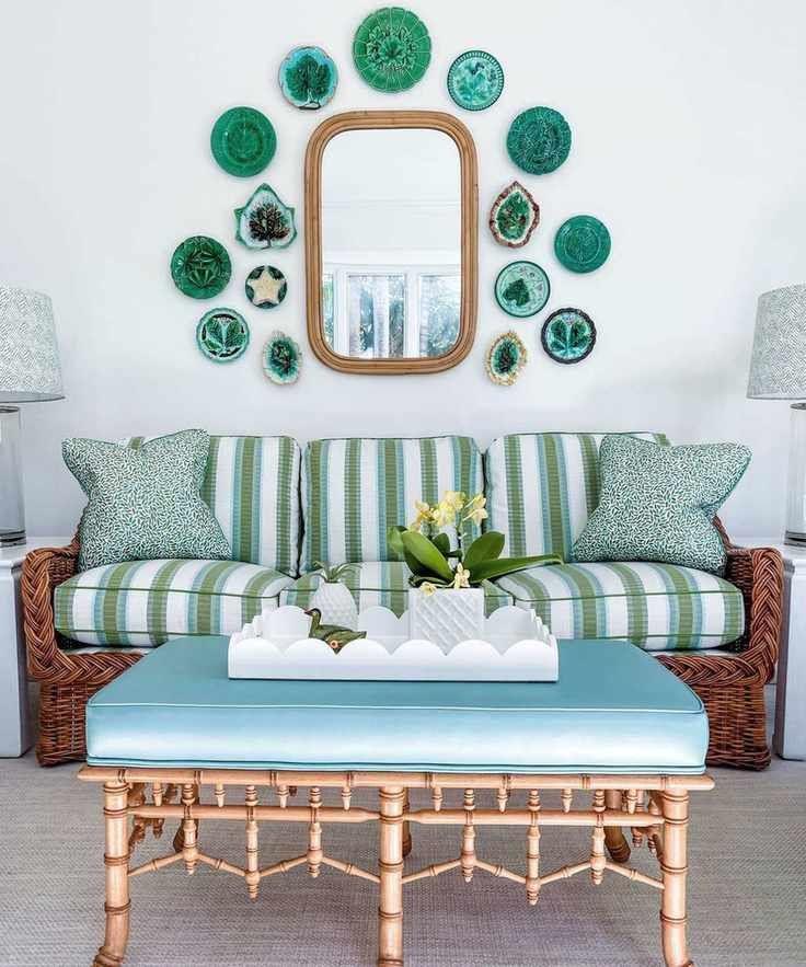 Coastal living room in blue and green with bamboo table, rattan sofa with striped cushions and majollica plate wall in green