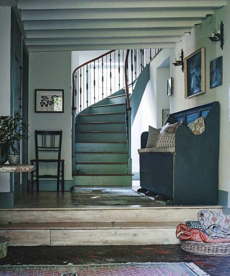 A blue-toned entryway with a curved wooden staircase and blue walls with framed artworks.