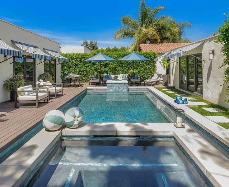 Pool house with entertainment areas and lounging beside a modern pool.