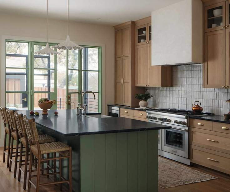 A wooden kitchen with a green island and green door frames