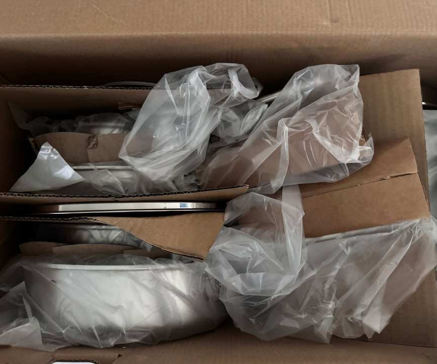 The inside of the GreenPan Thermobond pan box, with the pans packed in plastic bags and divided by cardboard.