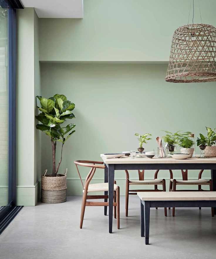 Dining room featuring a light green shade, light wood table with black metal frame, and matching bench.