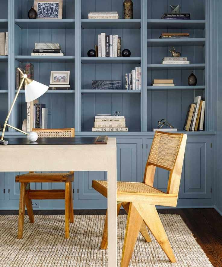 Home office with blue shelves, wooden midcentury chairs and angular table lamp