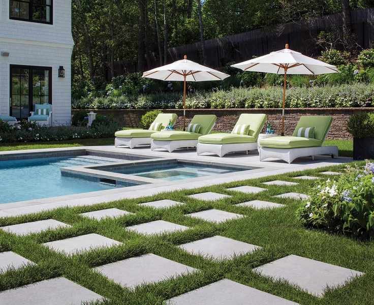 Pale green and white loungers by a pool with square paving stones.