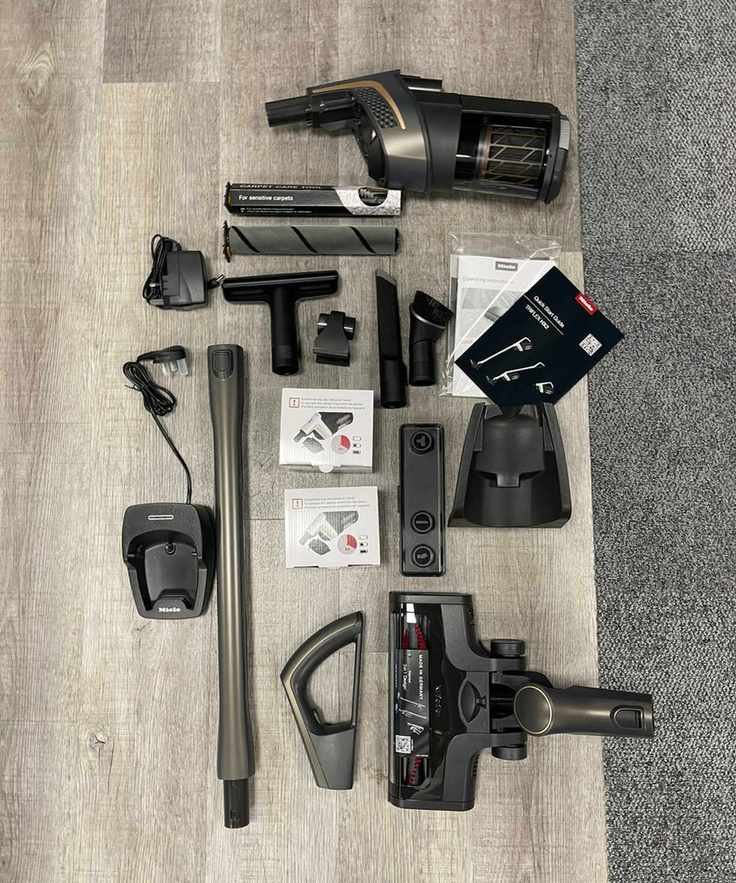 Miele Triflex HX2 Pro all parts and attachments laid out on wooden floor and carpet