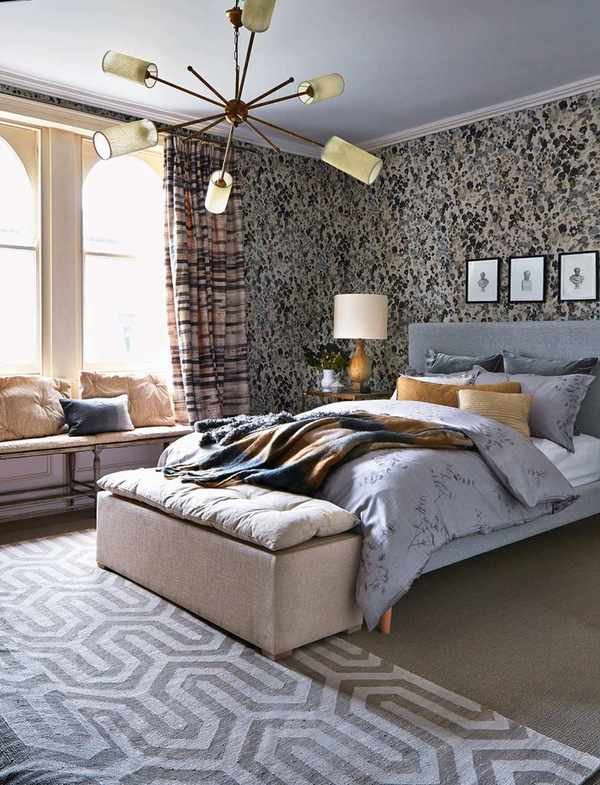 A sleek bedroom featuring a sputnik chandelier above a stylish gray bed