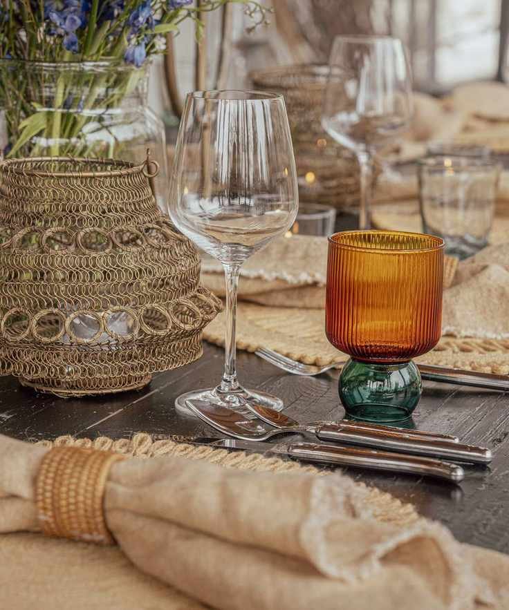 Table set with raffia table mats and linens in neutral colors and orange and green water glasses
